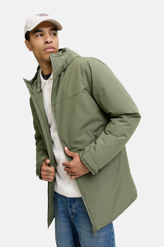 Groene korte jas van ORIGINALS BY JACK & JONES, met capuchon, gedragen met een witte polo en jeans.
