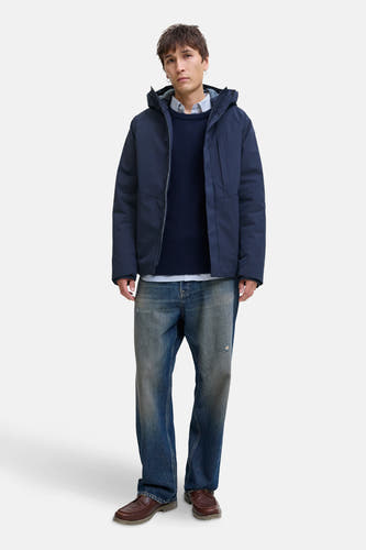 Blauwe korte jas van CORE BY JACK & JONES, gedragen over een trui en overhemd, gecombineerd met jeans en bruine schoenen.
