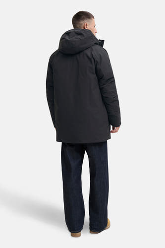 Zwarte lange jas van ORIGINALS BY JACK & JONES, met capuchon, gezien van achteren, gecombineerd met wijde jeans en beige schoenen.