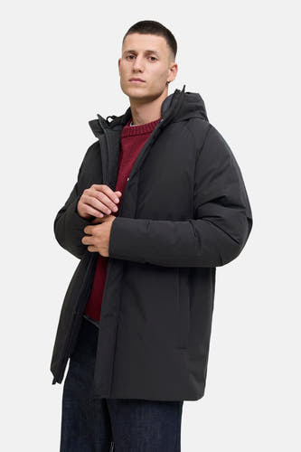 Zwarte lange jas van ORIGINALS BY JACK & JONES, met capuchon en een rode trui eronder.
