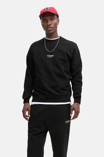 Gilet noir de CORE BY JACK & JONES, avec des détails blancs sur la en et le bas, associé à une chaîne et un chapeau rouge.