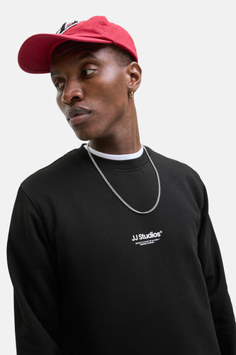 Gilet noir de CORE BY JACK & JONES, avec une chaîne argentée et un chapeau rouge.
