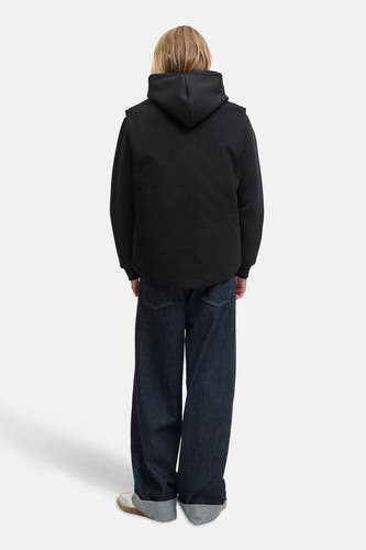 Zwarte bodywarmer van PREMIUM BLUE by JACK & JONES, met een capuchon, gecombineerd met wijde jeans en sneakers.