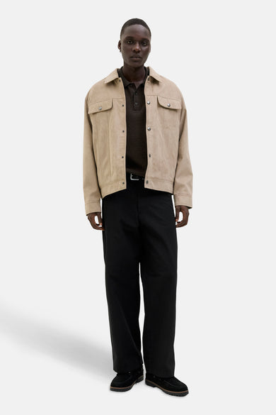 Bruine trui met V-hals van CORE BY JACK & JONES, gedragen onder een beige jas met zwarte broek en mocassins.
