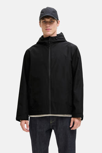 Zwarte korte jas van ORIGINALS BY JACK & JONES, met capuchon, gecombineerd met een donkere jeans en een pet.
