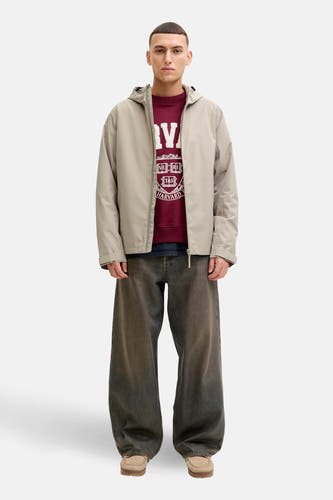 Beige korte jas van ORIGINALS BY JACK & JONES, met een capuchon, gedragen over een bordeauxrode sweater met een Harvard logo.