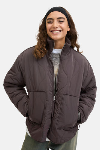 Manteau court en coton épais et gris de JJXX, avec une fermeture éclair et des poches, porté sur un pull gris avec un col blanc.