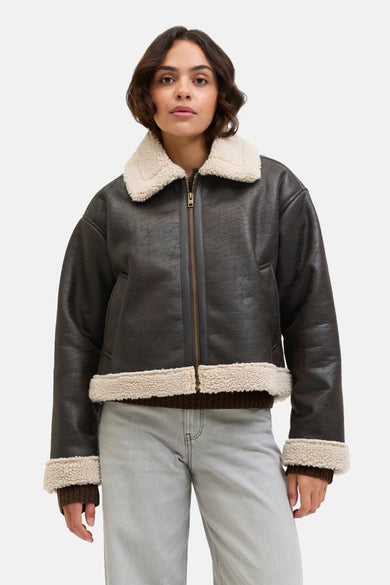 Bruine korte jas van JJXX, met lange mouwen, een witte kraag en grijze jeans.
