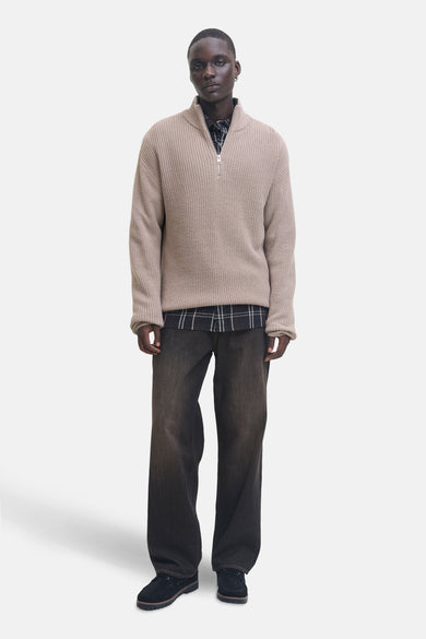 Beige trui van PREMIUM by JACK & JONES, gedragen over een geruit overhemd en met wijde jeans.
