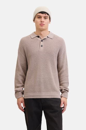 Pull beige à col V de PREMIUM par JACK & JONES, avec une texture tricotée et porté avec un chapeau et un pantalon noir.