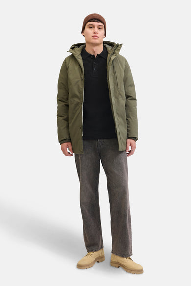 Zwarte trui met V-hals van PREMIUM by JACK & JONES, gedragen met een olijfgroene jas, een muts en een grijze broek.