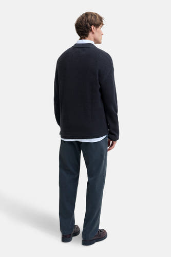 Pull à col V bleu de PREMIUM par JACK & JONES, avec un chemisier blanc visible en dessous, associé à une pantalon foncé.