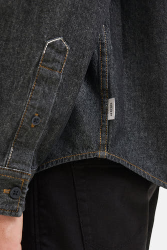 T-shirt en denim noir de JJREBEL, avec fermeture à boutons et étiquette de marque sur le côté.