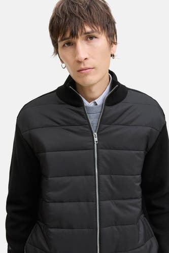 Zwart gilet van CORE BY JACK & JONES, met gewatteerd voorpand en gebreide mouwen, over een overhemd en trui.
