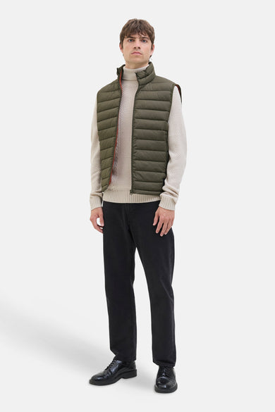 Gilet bodywarmer de JJREBEL, porté sur une veste beige et associé à un pantalon noir et des chaussures.