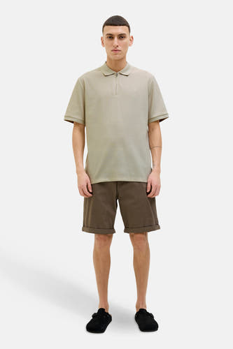 Beige polo met korte mouwen van PREMIUM by JACK & JONES, gedragen met bruine shorts en zwarte instappers.