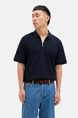 Blauwe polo van PREMIUM by JACK & JONES, met een rits en gedragen met een bruine riem en jeans.
