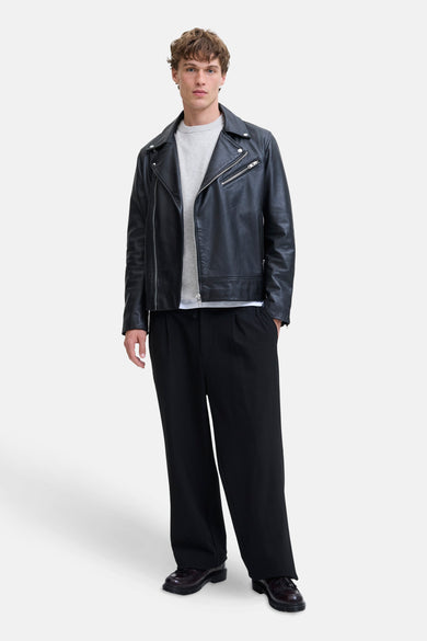 Sweat-shirt gris avec col rond de PREMIUM by JACK & JONES, sous une veste en cuir noire et un pantalon large.