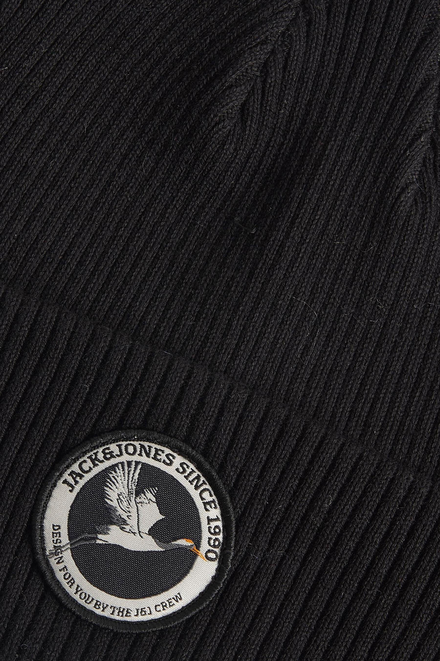 Zwarte muts van ACCESSORIES BY JACK & JONES, met geribbelde textuur en een ronde merkbadge met vogelmotief.
