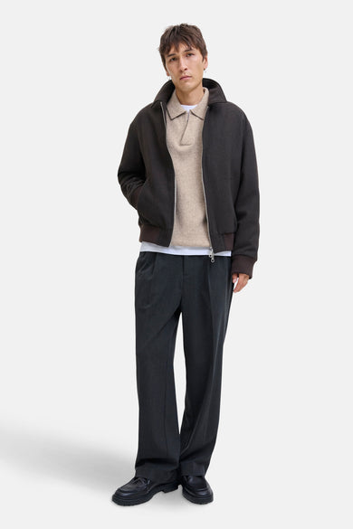 Beige trui met V-hals van ORIGINALS BY JACK & JONES, gedragen met een bruine jas en grijze pantalon.
