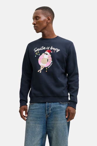 Pull-over bleu d'ORIGINALS BY JACK & JONES, avec un imprimé d'un Père Noël dans une baignoire et le texte "Santa is busy", porté avec des jeans.