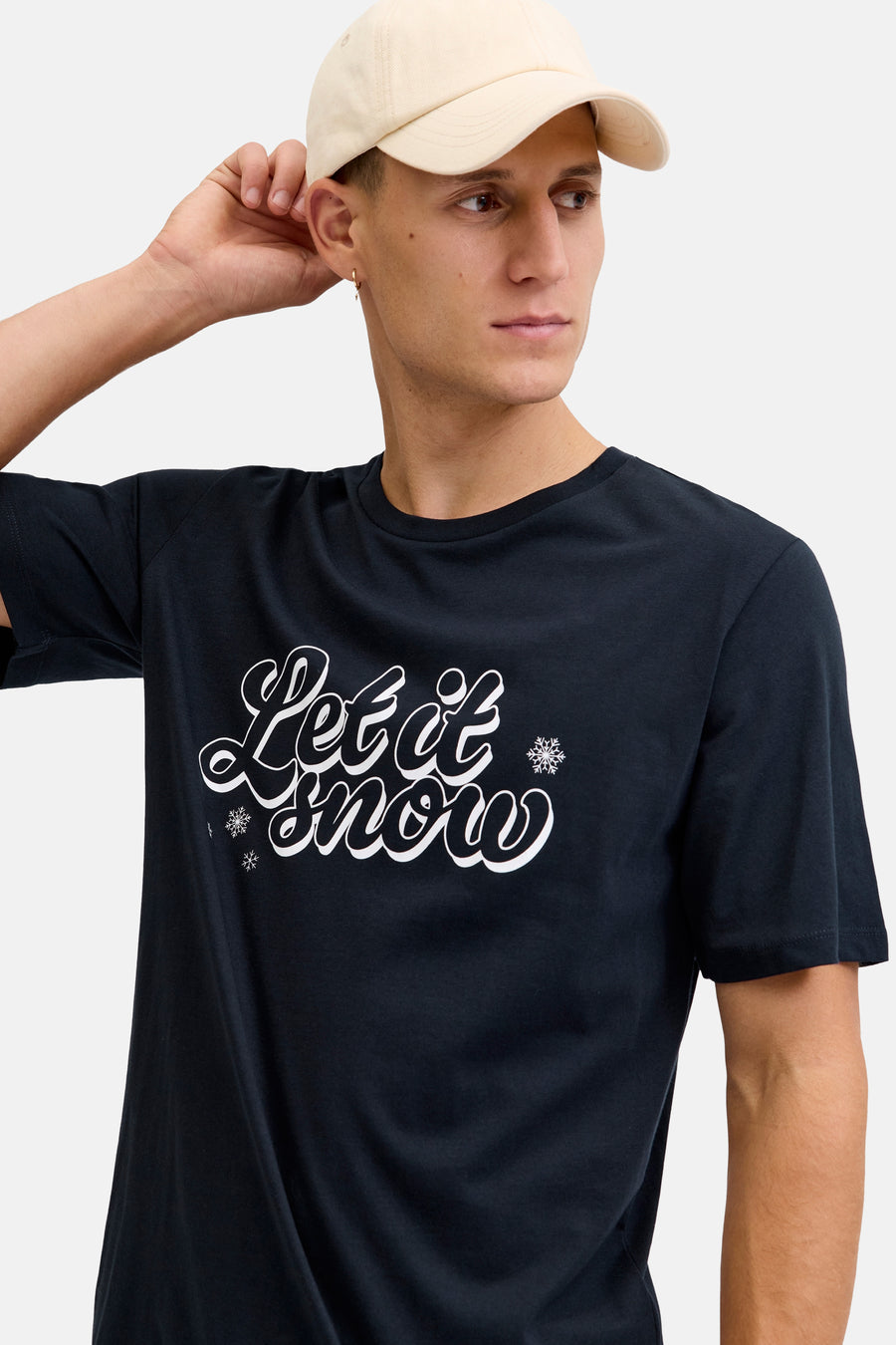Man met pet en zwart T-shirt met "Let it snow" tekst.
