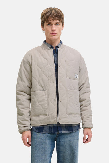 Beige korte jas van ORIGINALS BY JACK & JONES, met ruitjeshemd eronder en blauwe jeans.
