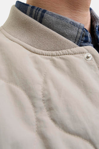 Beige, korte jas van ORIGINALS BY JACK & JONES, met ribgebreide kraag en zichtbare drukknoop, gedragen over een geruit overhemd.
