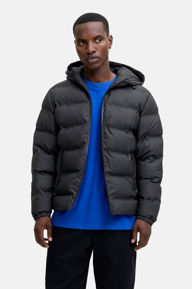 Manteau court noir de CORE BY JACK & JONES, avec capuche et porté sur un t-shirt bleu.