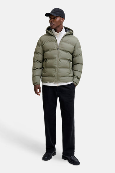 Manteau vert court de CORE BY JACK & JONES, avec capuche, porté sur une chemise blanche et un pantalon noir.