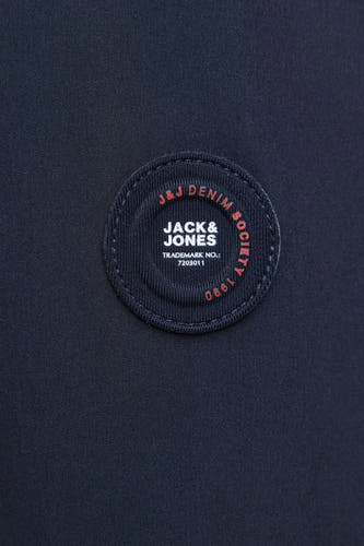 Blauwe korte jas van ORIGINALS BY JACK & JONES, detailopname van het logo-embleem met opschrift en jaartal.