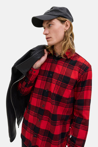 Rood geruit overhemd met lange mouwen van PREMIUM BLUE by JACK & JONES, met een zwarte leren jack over de schouder en zwarte pet.