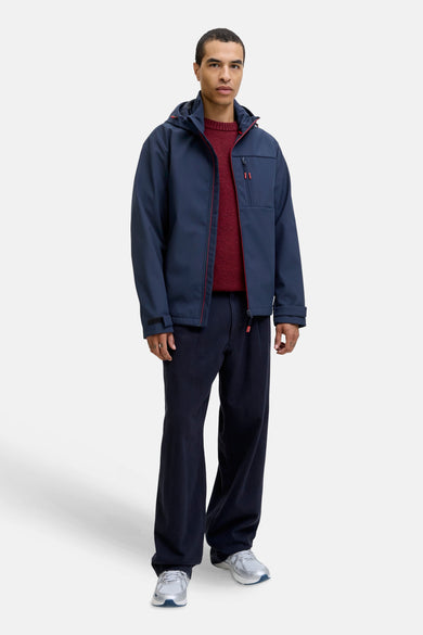 Blauwe korte jas van CORE BY JACK & JONES, met rode details en gedragen met een rode trui en donkere broek.
