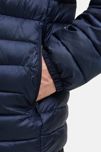 Blauwe korte jas van PREMIUM BLUE by JACK & JONES, met een hand in de zak en een gewatteerde textuur.
