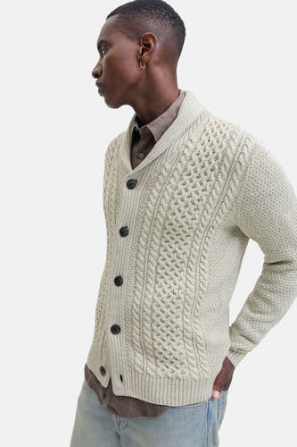 Gilet beige de PREMIUM BLUE par JACK & JONES, avec un motif côtelé et une fermeture à boutons, porté sur une chemise brune et un jean.