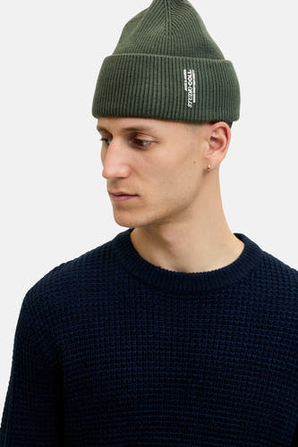 Groene muts van ACCESSORIES BY JACK & JONES, gedragen met een donkerblauwe trui en een gouden oorbel.

