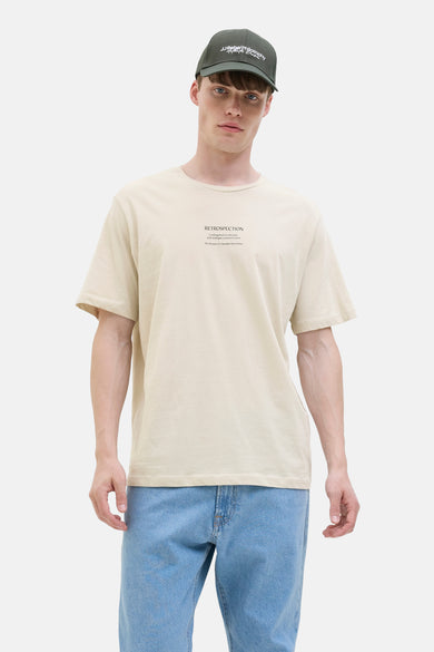 T-shirt écru à manches courtes de JJREBEL, associé à une casquette verte et un jeans bleu.