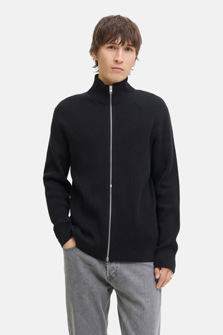 Zwart gilet van CORE BY JACK & JONES, met ritssluiting en grijze jeans.
