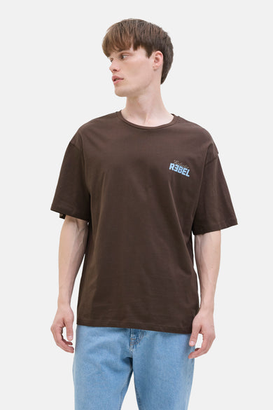 Bruin T-shirt met korte mouwen van JJREBEL, met een lichtblauwe print rechtsboven, gedragen met een blauwe jeans.
