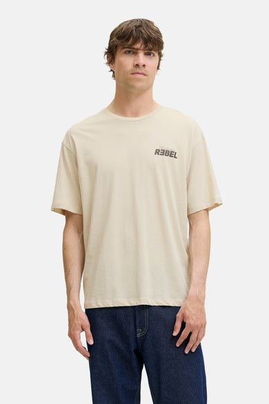 T-shirt écru à manches courtes de JJREBEL, avec un petit logo sur la poitrine et porté avec un jean foncé.