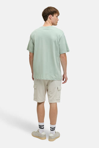 Groen T-shirt met korte mouwen van JJREBEL, gezien van achter, gecombineerd met beige shorts en witte sokken.
