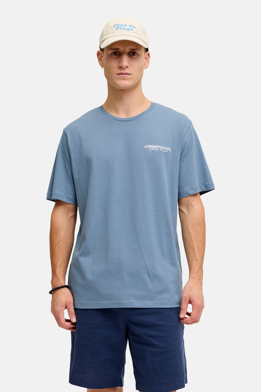 Blauw T-shirt met korte mouwen van JJREBEL, met een kleine print op de borst en een beige pet.
