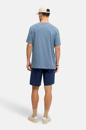 Blauw T-shirt met korte mouwen van JJREBEL, gezien van achteren met donkerblauwe shorts, sokken en sneakers.