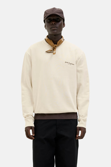 Ecru sweater van ORIGINALS BY JACK & JONES, met bruine bandana om de hals en zwarte broek.