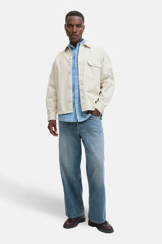 Beige overhemd van PREMIUM BLUE by JACK & JONES, gedragen over een blauw denim overhemd en wijde jeans.