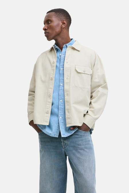 Beige overhemd van PREMIUM BLUE by JACK & JONES, gedragen over een blauw denim overhemd met jeans.
