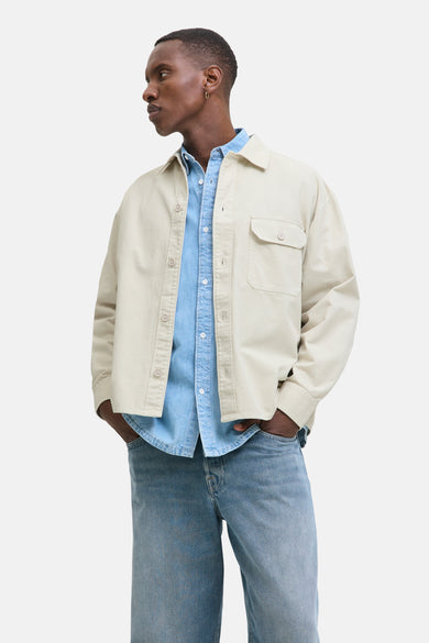 Beige overhemd van PREMIUM BLUE by JACK & JONES, gedragen over een blauw denim overhemd met jeans.