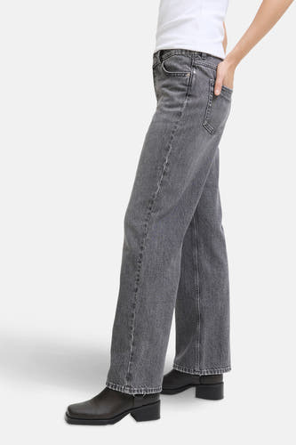 Jean droit gris de JJXX, avec une main dans la poche, associé à des bottes en cuir noires.