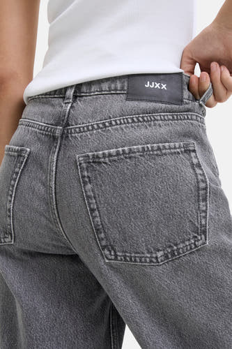 Jean droit gris de JJXX, avec un lavage vintage et des poches arrière, porté avec une chemise blanche.