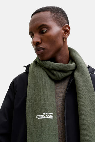 Groene wintersjaal van ACCESSORIES BY JACK & JONES, met merklogo, gedragen met een zwarte jas en bruine trui.